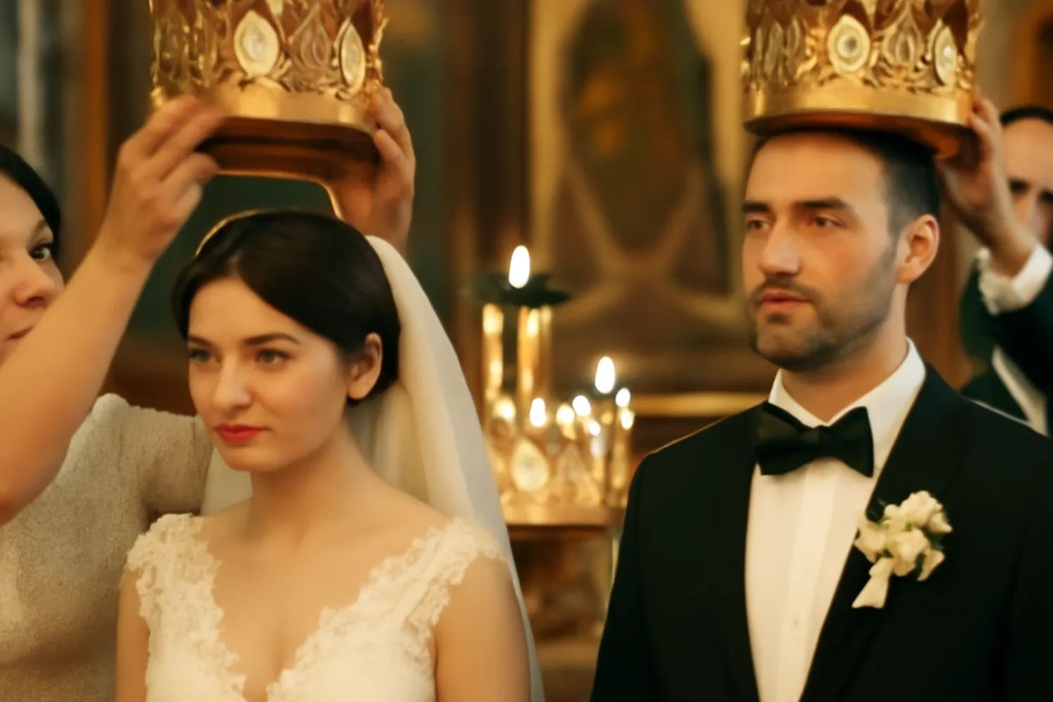 Godparents holding crowns above the couple during venchanie
